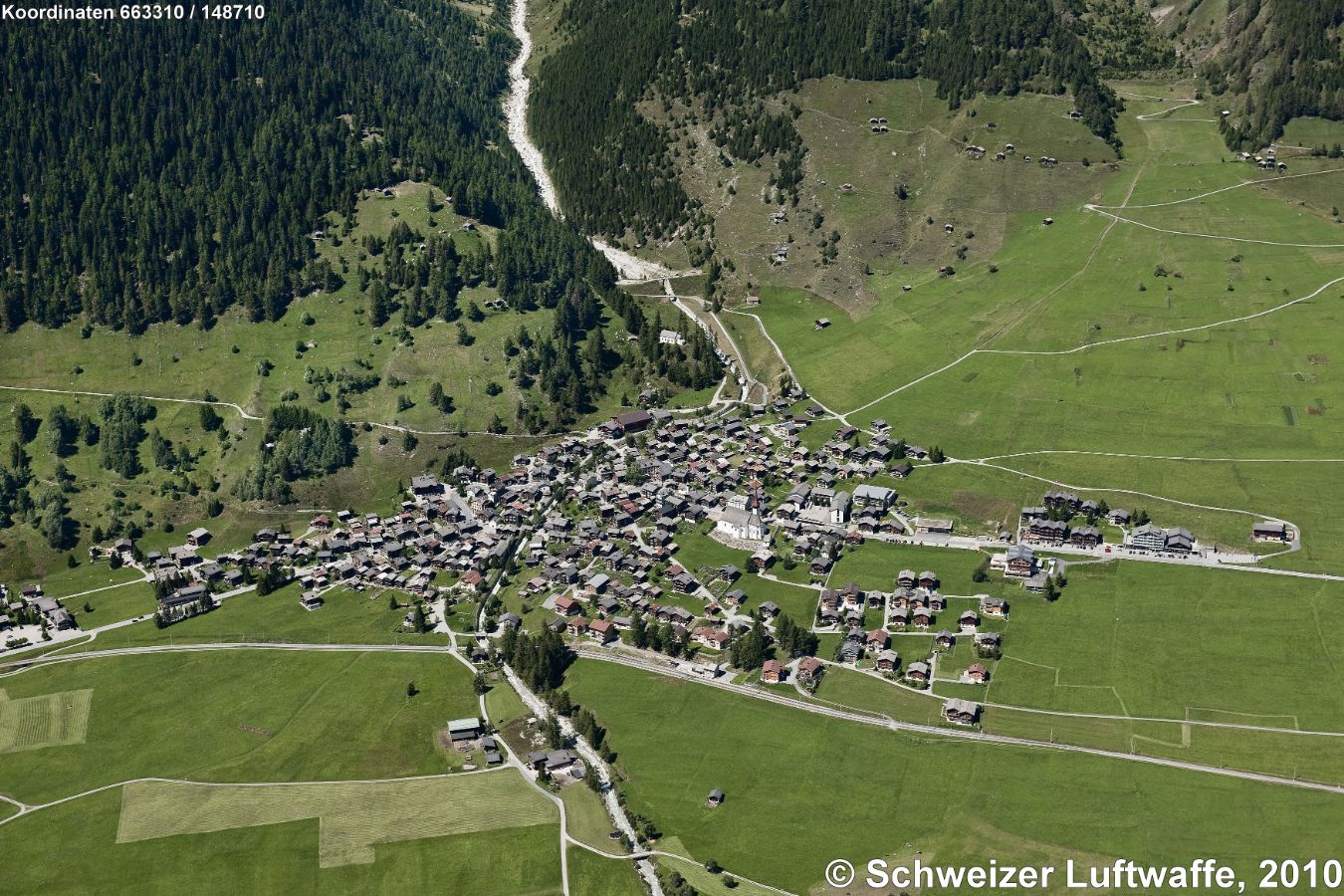 Münster (VS); (Position 2'663'408.59, 1'148'767.27). Das Ortsbild ist von nationaler Bedeutung. Die zahlreichen, typischen Holzhäuser, sgn. 'Gommerhäuser'. Die aus Lärchenholz erbauten Einzweckbauten (Wohnen, Speicher, Stall) sind dendrochronologisch datiert. Hier steht das älteste bekannte Holzhaus des Wallis aus dem Jahr 1369. - Bekannt ist auch die Pfarrkirche (Bildmitte) aus dem 13. Jahrhundert mit einem spätgotischen Hochaltar.